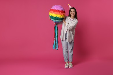 Photo of Happy woman with colorful pinata on pink background