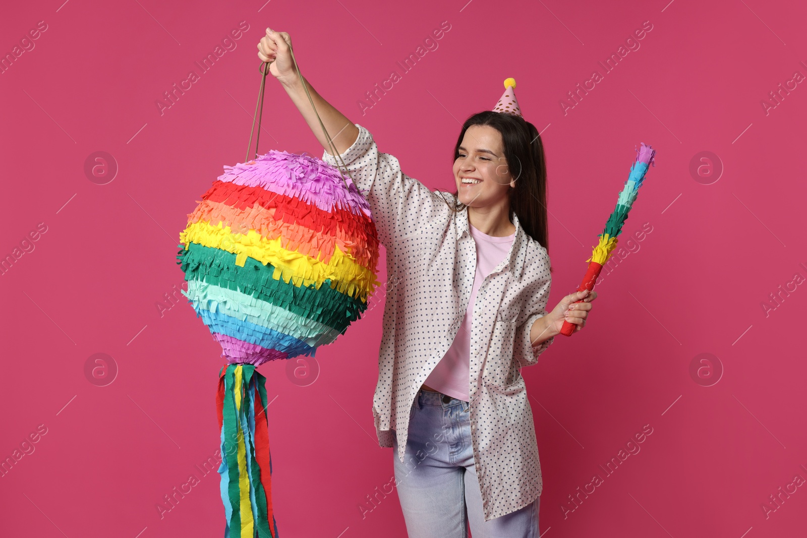 Photo of Happy woman with colorful pinata and stick on pink background