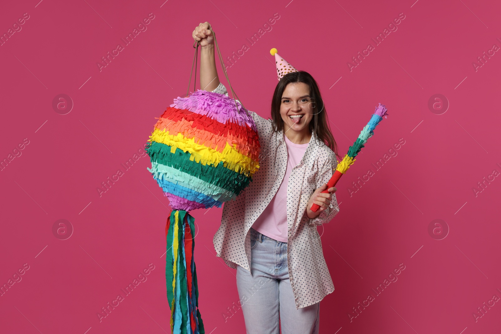 Photo of Happy woman with colorful pinata and stick on pink background