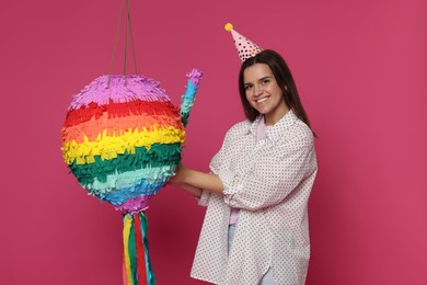 Photo of Happy woman with colorful pinata and stick on pink background