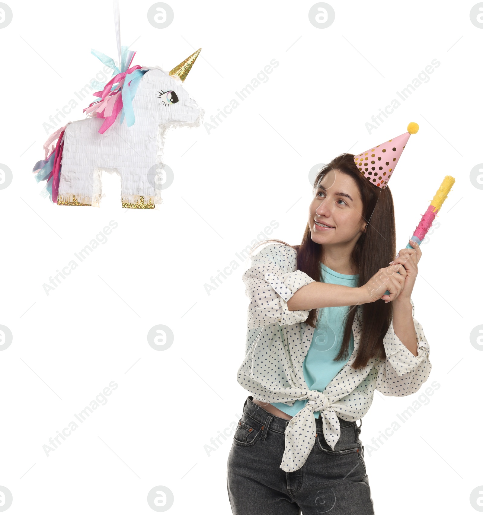 Photo of Happy woman hitting unicorn shaped pinata with stick on white background