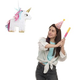 Photo of Happy woman hitting unicorn shaped pinata with stick on white background