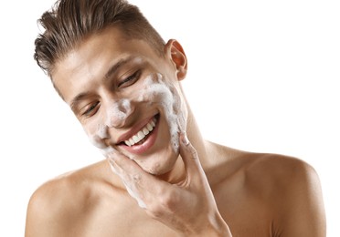 Photo of Smiling man washing his face with cleansing foam on white background