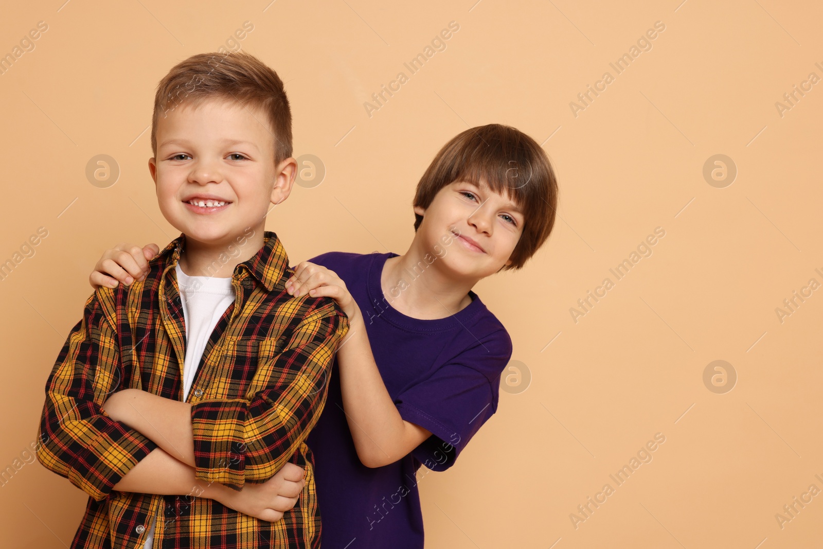 Photo of Portrait of cute brothers on beige background. Space for text