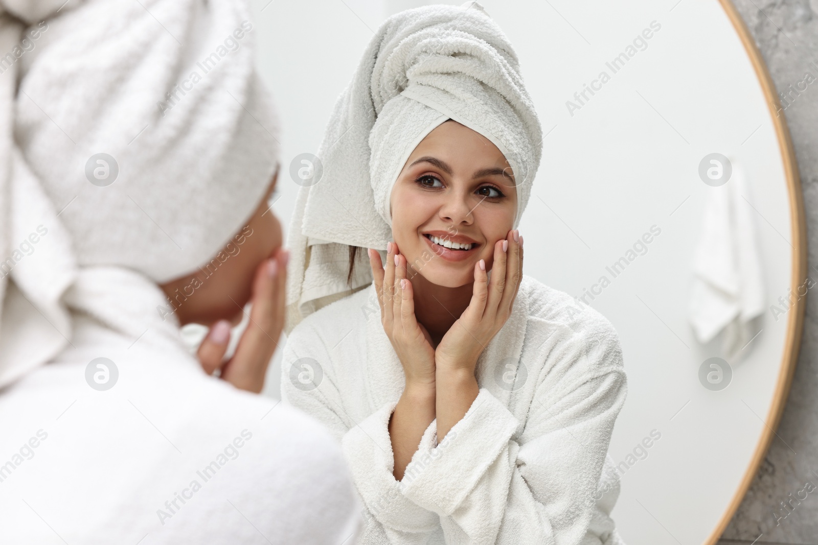 Photo of Washing face. Happy woman looking at mirror in bathroom