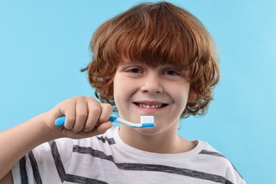 Photo of Cute boy with toothbrush on light blue background