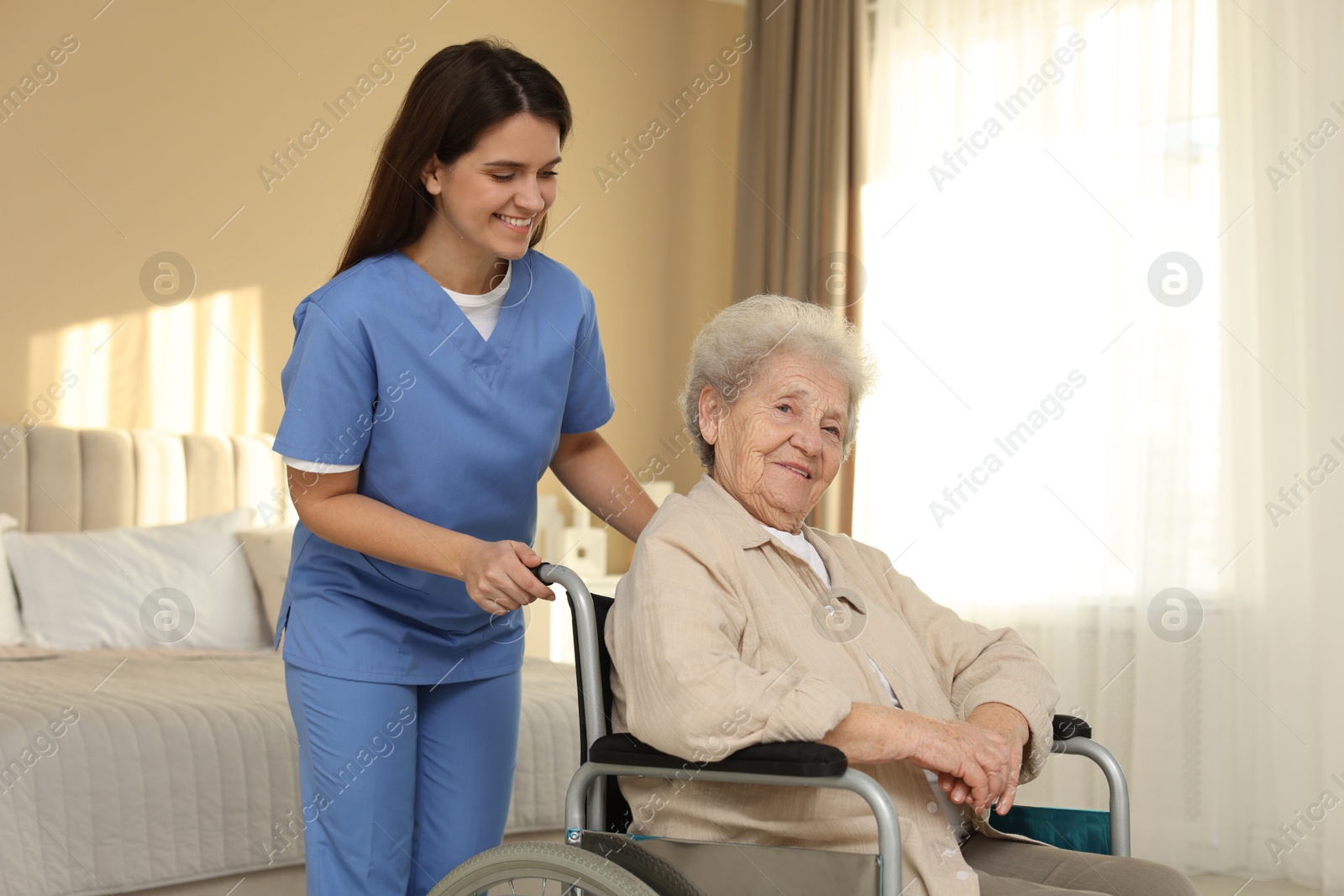 Photo of Healthcare worker with elderly woman in wheelchair indoors