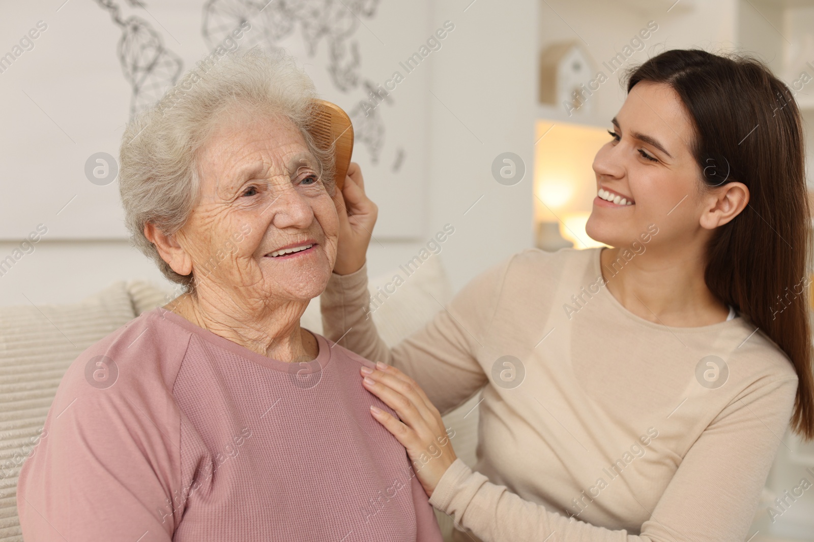 Photo of Granddaughter brushing her grandmother with comb at home. Elderly care