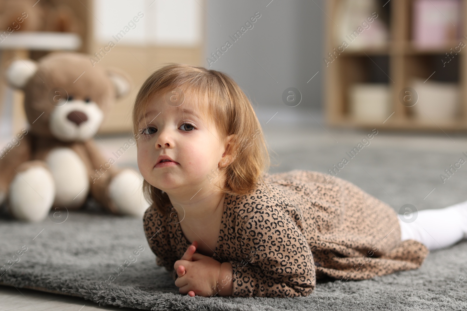 Photo of Cute little girl on floor at home