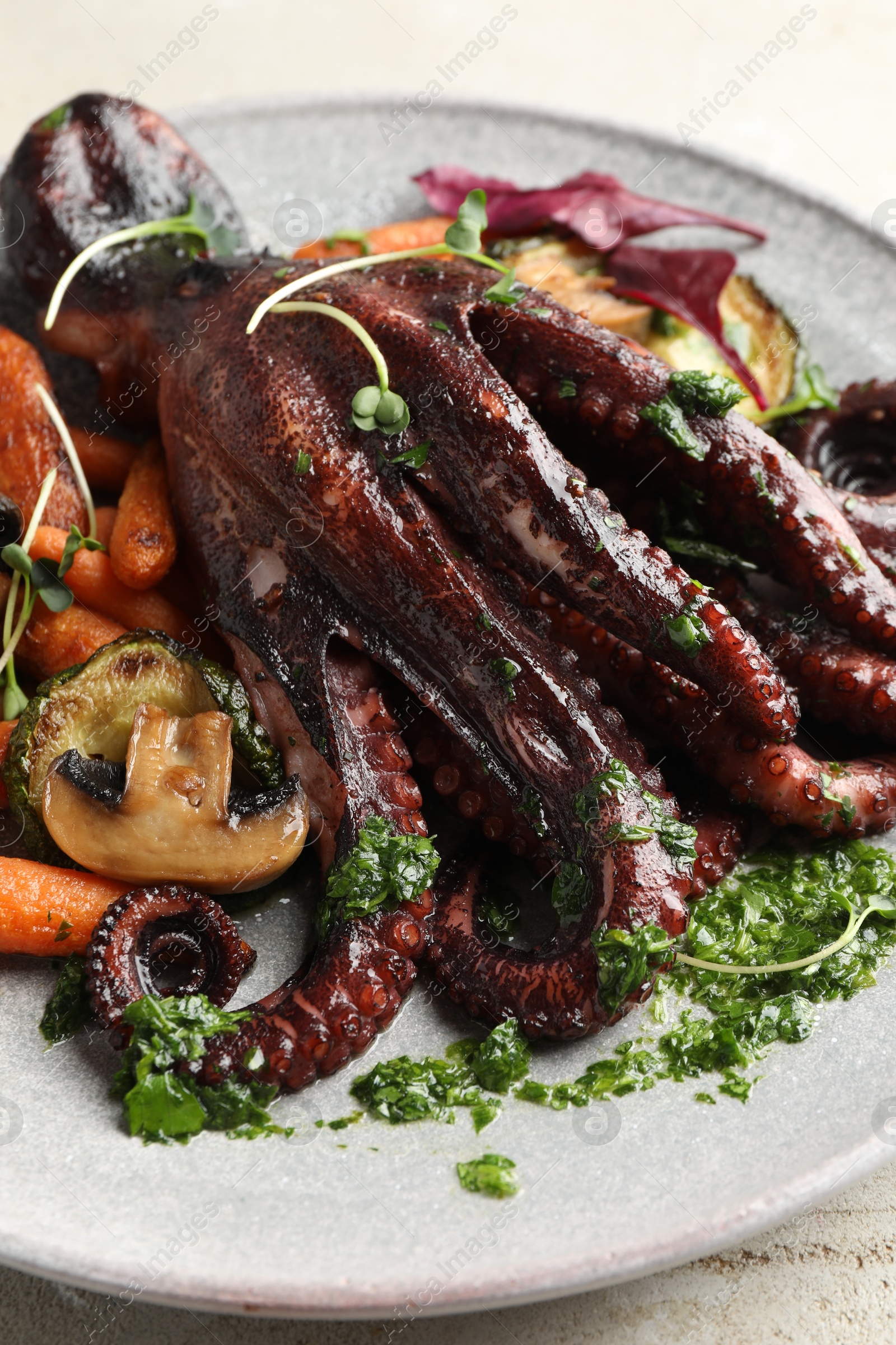 Photo of Roasted octopus with vegetables and mushrooms on table, closeup