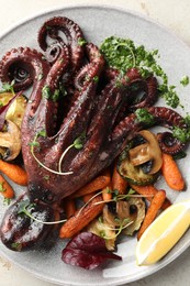 Photo of Roasted octopus with vegetables and mushrooms on light grey table, top view