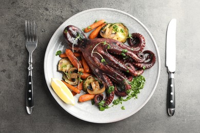 Photo of Roasted octopus served with vegetables and mushrooms on grey table, flat lay