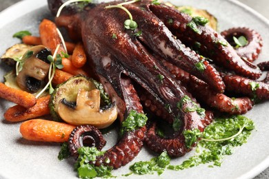 Photo of Roasted octopus with vegetables and mushrooms on plate, closeup