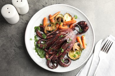 Roasted octopus served with vegetables and mushrooms on grey table, flat lay