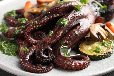 Photo of Roasted octopus with vegetables on table, closeup