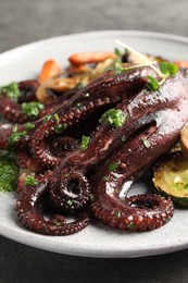 Photo of Roasted octopus with vegetables on table, closeup