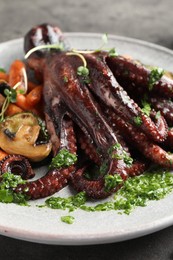 Photo of Roasted octopus with vegetables on table, closeup