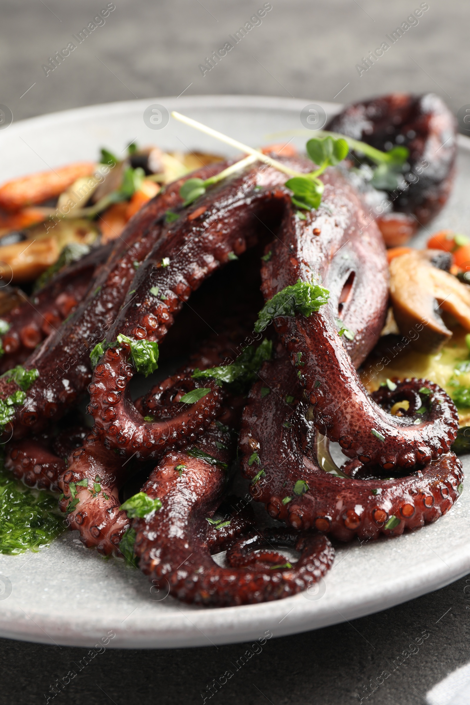 Photo of Roasted octopus with vegetables and mushrooms on table, closeup