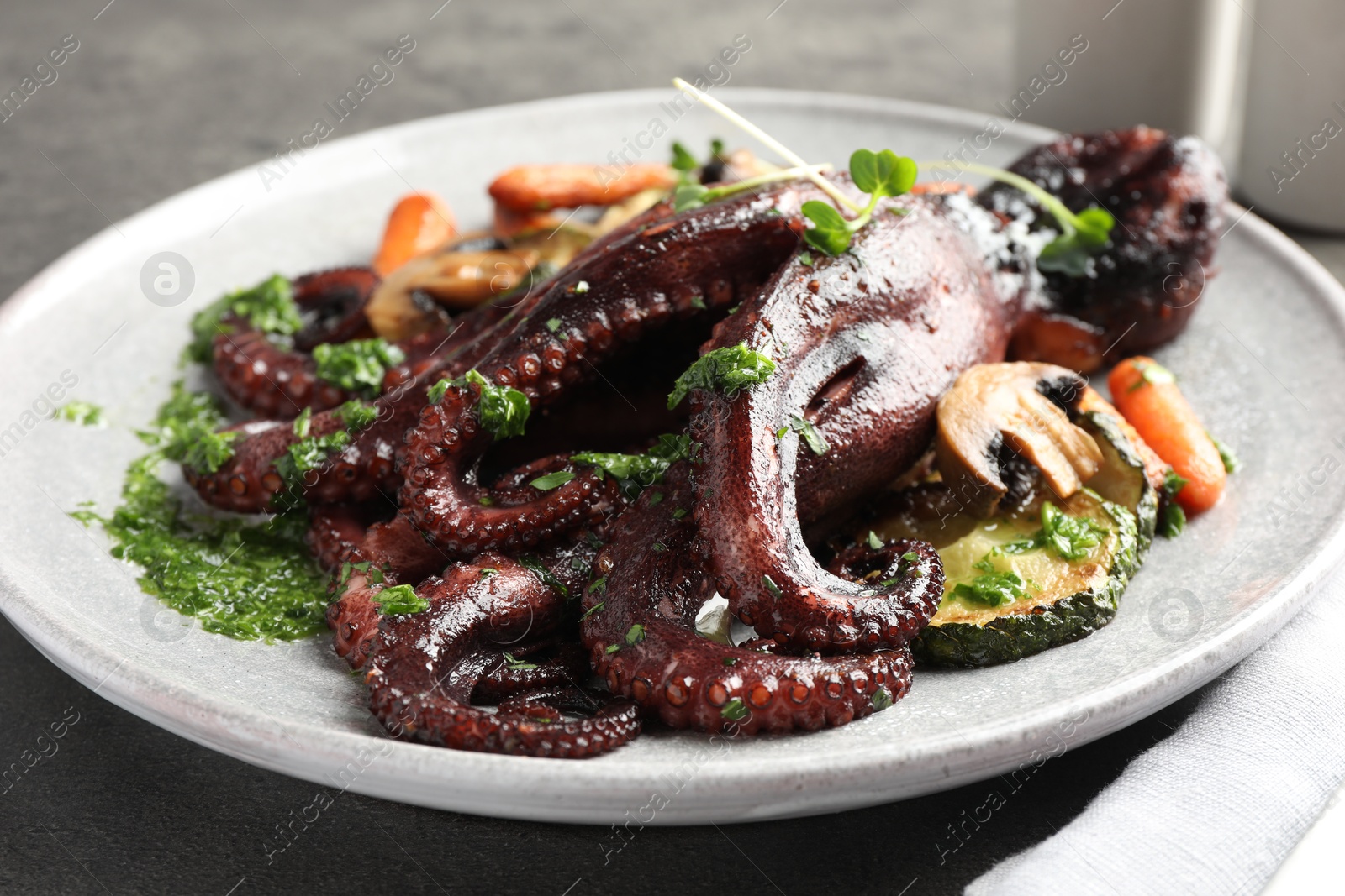 Photo of Roasted octopus with vegetables and mushrooms on table, closeup