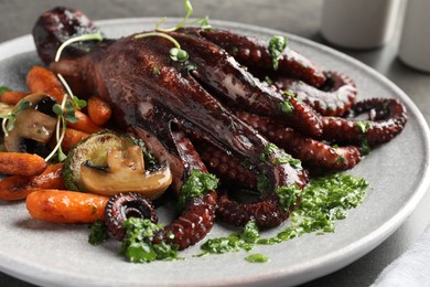 Photo of Roasted octopus with vegetables and mushrooms on table, closeup