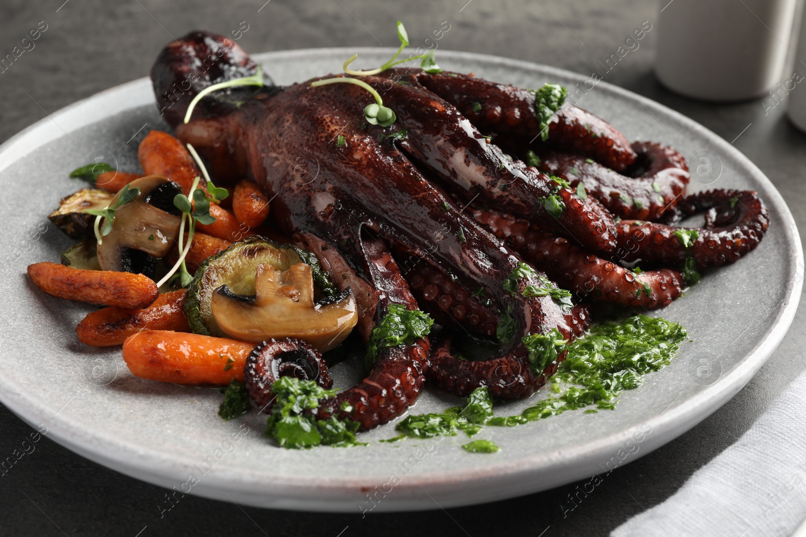 Photo of Roasted octopus with vegetables and mushrooms on table, closeup