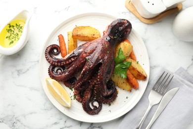 Photo of Roasted octopus with vegetables served on white marble table, flat lay