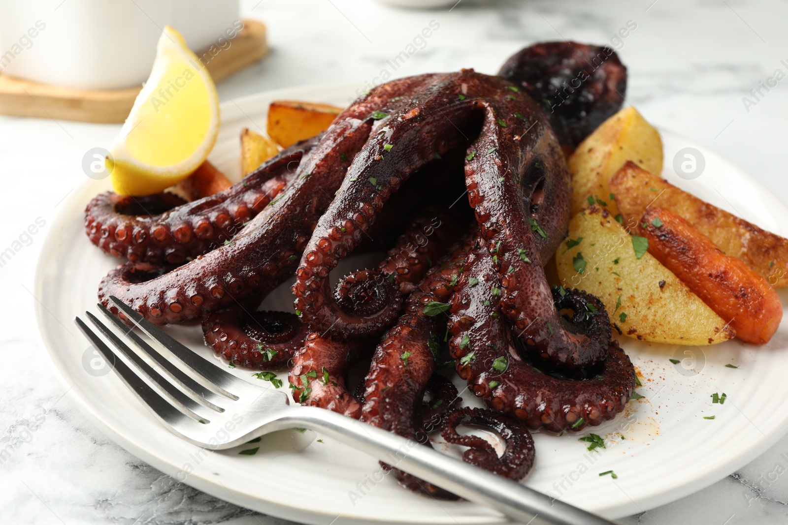 Photo of Roasted octopus with vegetables on white marble table, closeup