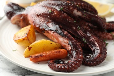 Photo of Roasted octopus with vegetables on white marble table, closeup