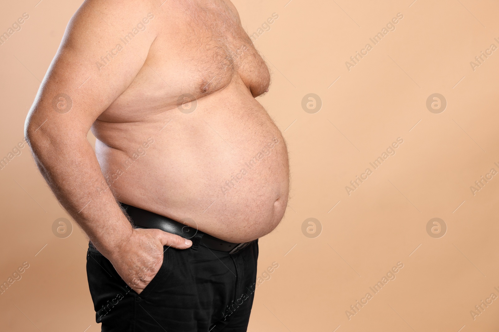 Photo of Overweight problem. Man with excessive belly fat on beige background, closeup. Space for text