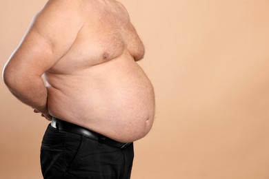 Photo of Overweight problem. Man with excessive belly fat on beige background, closeup. Space for text