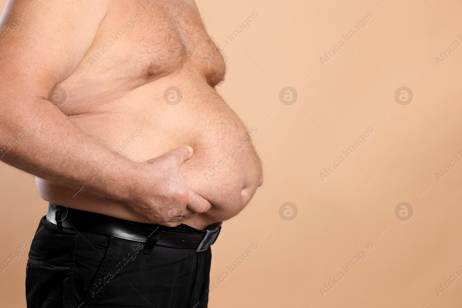 Photo of Overweight problem. Man with excessive belly fat on beige background, closeup. Space for text