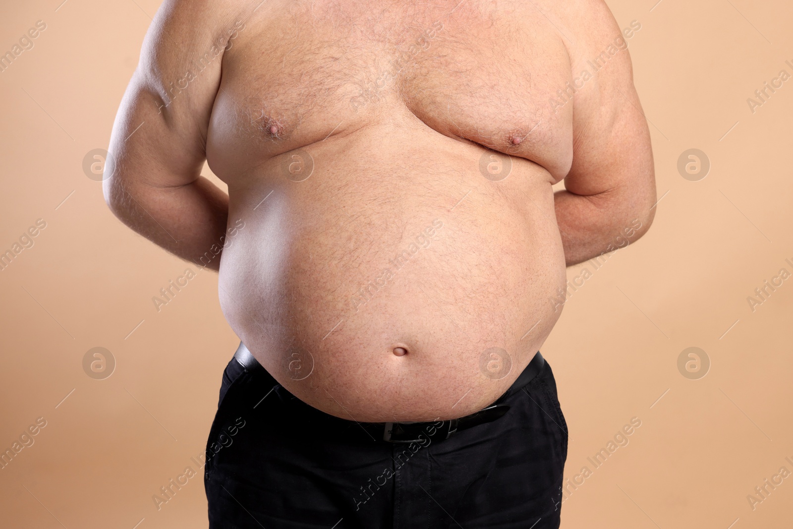 Photo of Man with excessive belly fat on beige background, closeup. Overweight problem