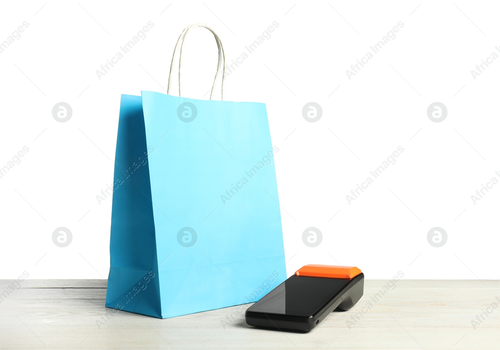 Photo of Payment terminal and shopping bag on wooden table against white background