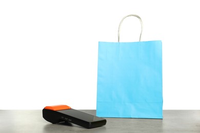 Photo of Payment terminal and shopping bag on grey table against white background