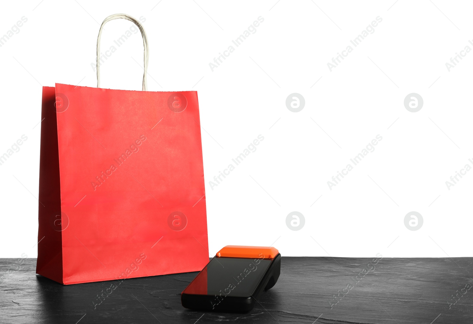 Photo of Payment terminal and shopping bag on black table against white background