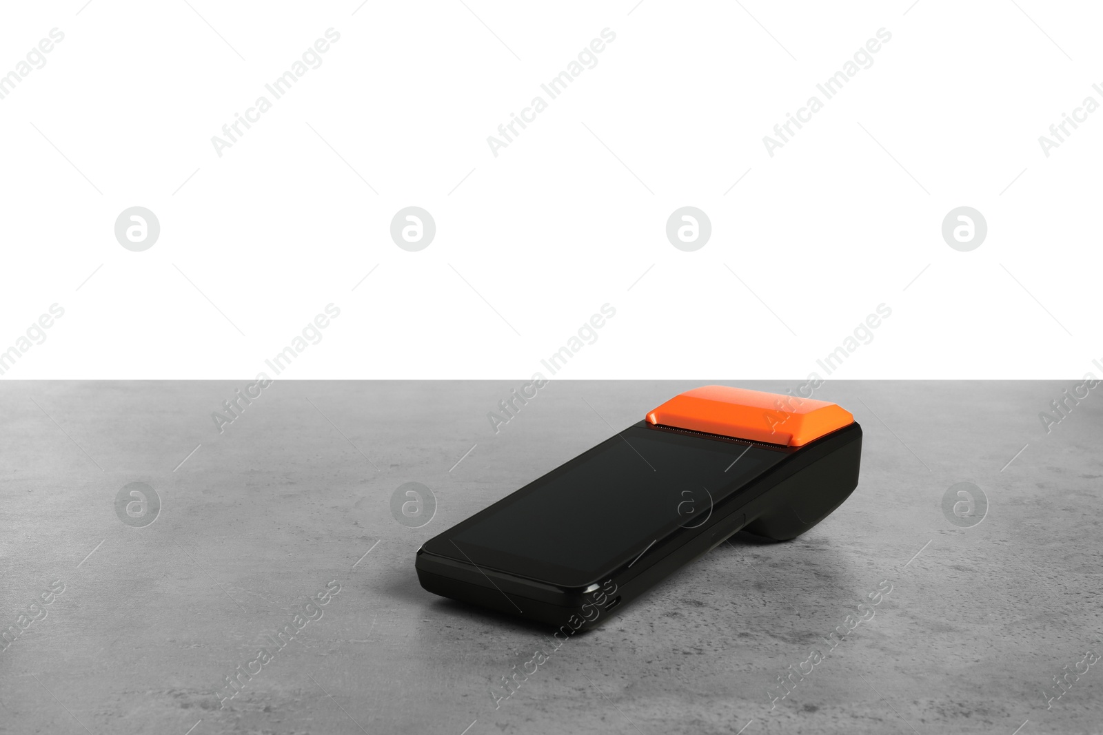 Photo of Payment terminal on grey table against white background