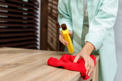 Photo of Woman polishing wooden table at home, closeup