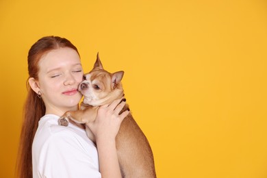 Photo of Teenage girl with her cute Chihuahua dog on yellow background, space for text