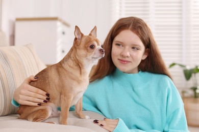 Photo of Teenage girl with her cute Chihuahua dog on sofa at home, selective focus