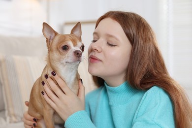 Photo of Teenage girl with her cute Chihuahua dog on sofa at home