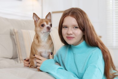 Photo of Teenage girl with her cute Chihuahua dog on sofa at home