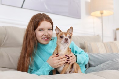 Teenage girl with her cute Chihuahua dog on sofa at home