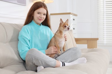 Teenage girl with her cute Chihuahua dog on sofa at home