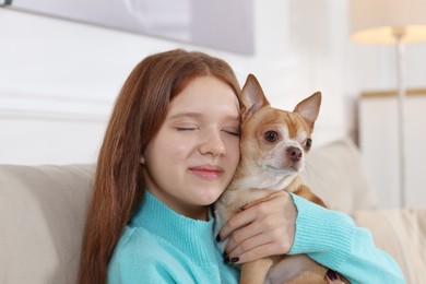 Photo of Teenage girl with her cute Chihuahua dog on sofa at home