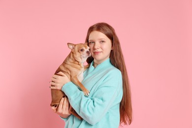 Photo of Teenage girl with her cute Chihuahua dog on pink background