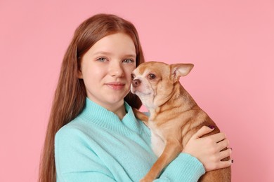 Photo of Teenage girl with her cute Chihuahua dog on pink background