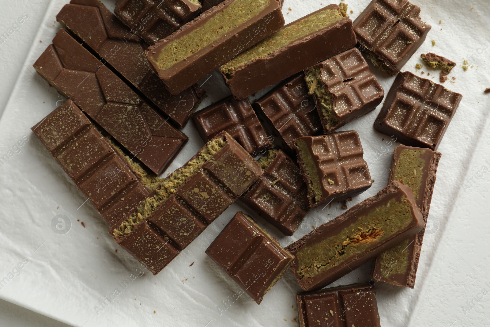 Photo of Pieces of tasty Dubai chocolate with pistachios and knafeh on white table, top view