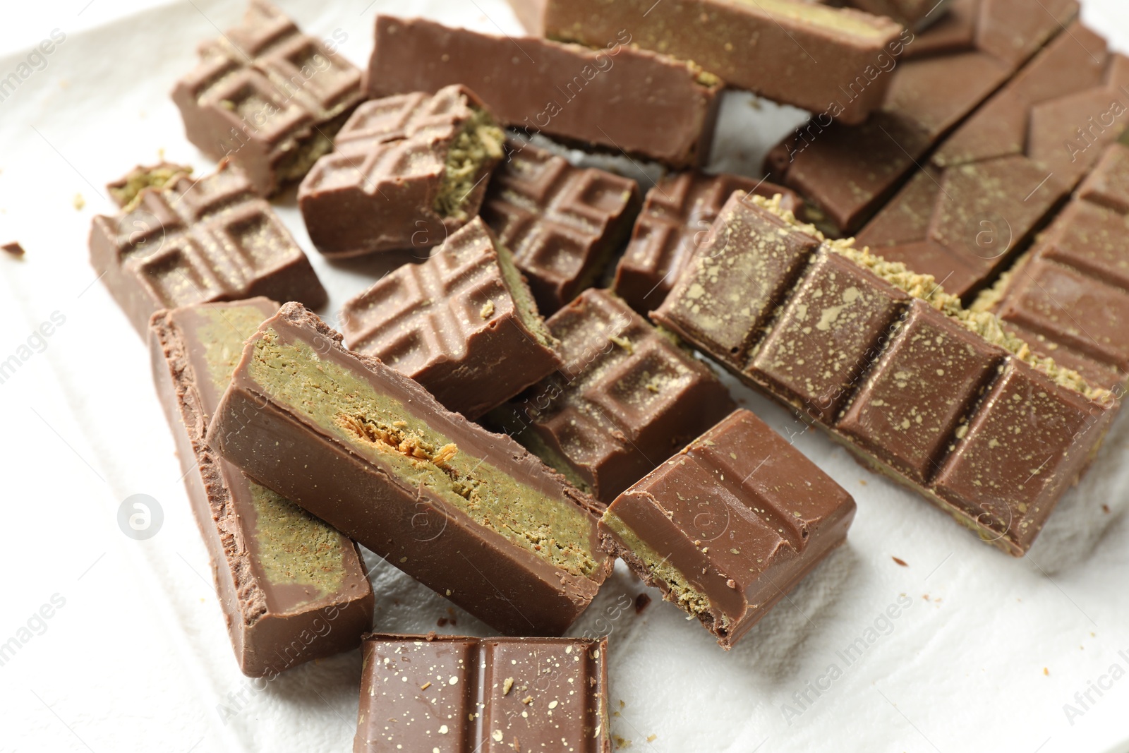 Photo of Pieces of tasty Dubai chocolate with pistachios and knafeh on plate, closeup