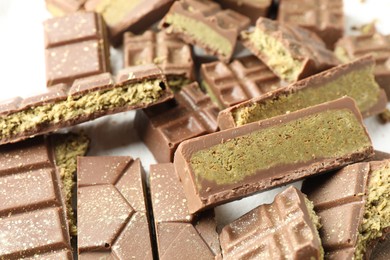 Pieces of tasty Dubai chocolate with pistachios and knafeh on white table, closeup