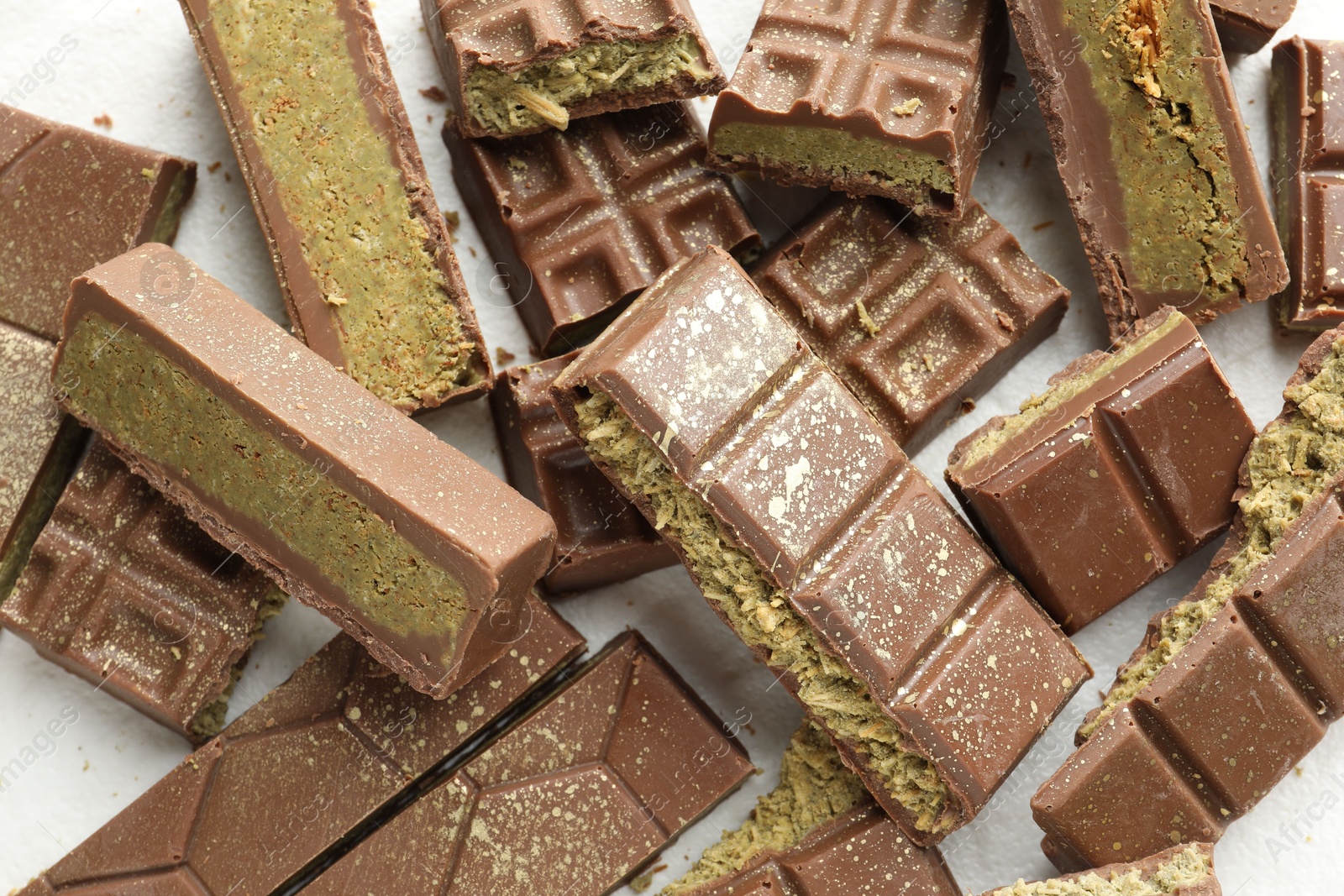 Photo of Pieces of tasty Dubai chocolate with pistachios and knafeh on white table, top view